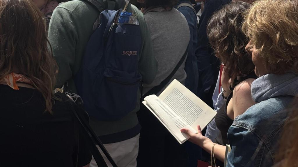 Una mujer lee mientras hace cola para la firma de Milena Busquets