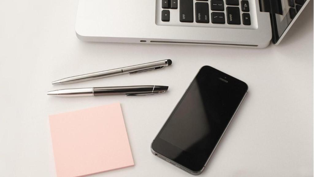 Ordenador, notas, móvil y bolígrafos
