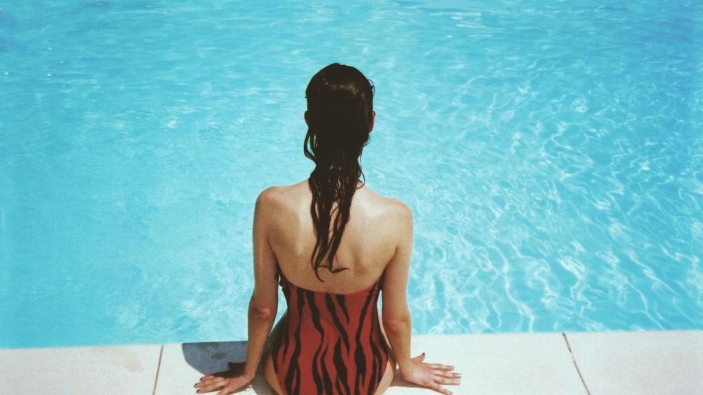 Mujer disfruta sentada junto a una piscina