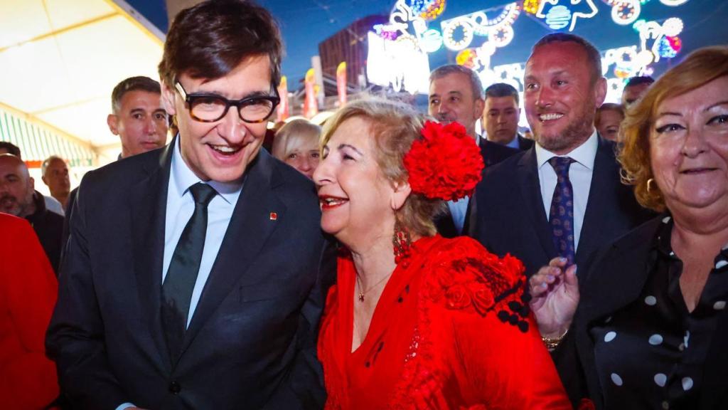El presidente Illa conversa con una mujer vestida de flamenca en la Feria de Abril del Fórum