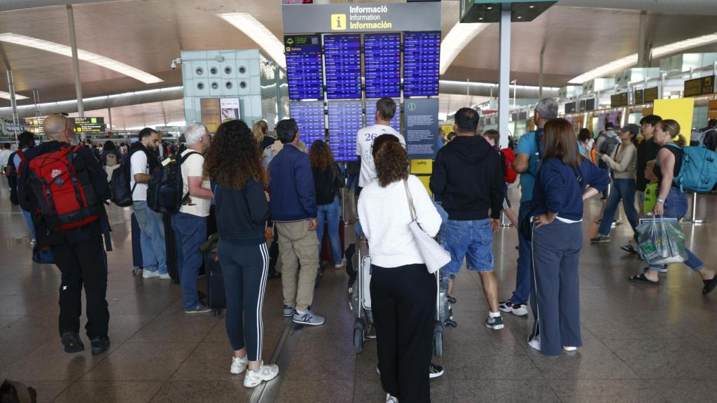 Viajeros verificando las pantallas de información en El Prat, hoy lunes