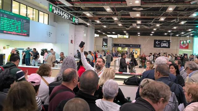 Un trabajador de Renfe intenta coordinar el tráfico de pasajeros en la estación de Sants, en Barcelona.