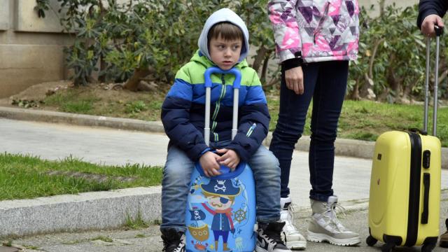 Un niño refugiado junto a su maleta, en Barcelona