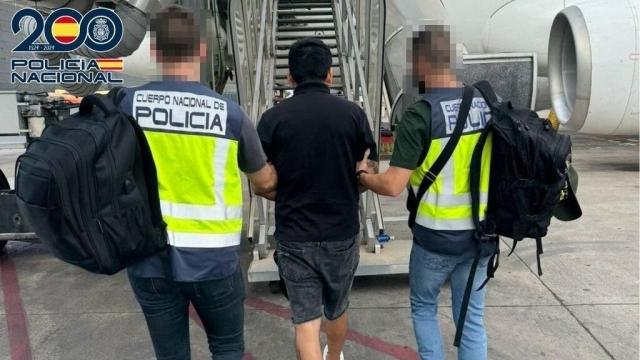 Dos policías conducen a uno de los ciudadanos deportados hasta el avión