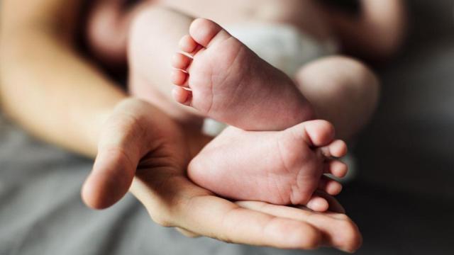 Unas manos sostienen los pies de un recién nacido