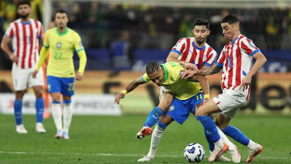 Raphinha intenta superar a dos defensores de Paraguay