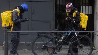 Dos repartidores de Glovo esperando fuera de un local