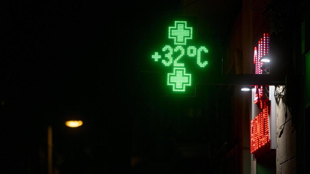 Un termómetro marca 32 grados centígrados en una farmacia del Paseo Maragall de Barcelona, en una medianoche