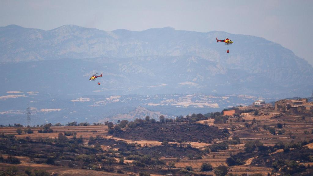Helicópteros de bomberos tratan de apagar los restos del incendio de Torrefeta i Florejacs, Lleida