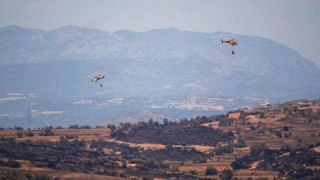 Helicópteros de bomberos tratan de apagar los restos del incendio de Torrefeta i Florejacs, Lleida