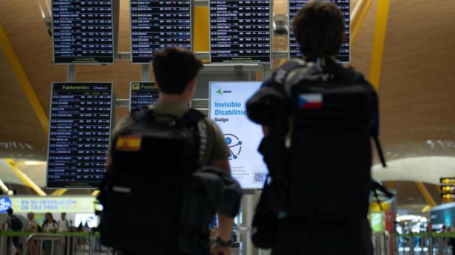 Dos jóvenes observan el panel informativo de un aeropuerto