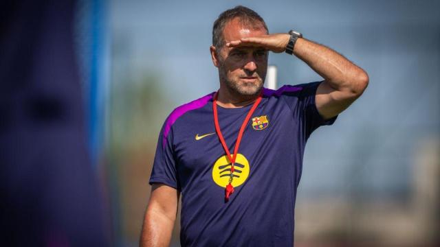 Hansi Flick se tapa el sol de la cara con la mano para observar a sus futbolistas