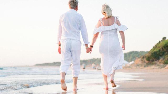 Una pareja mayor pasea junto al mar al atardecer