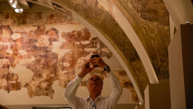 Un hombre fotografía las pinturas del Monasterio de Sijena, expuestas en el MNAC