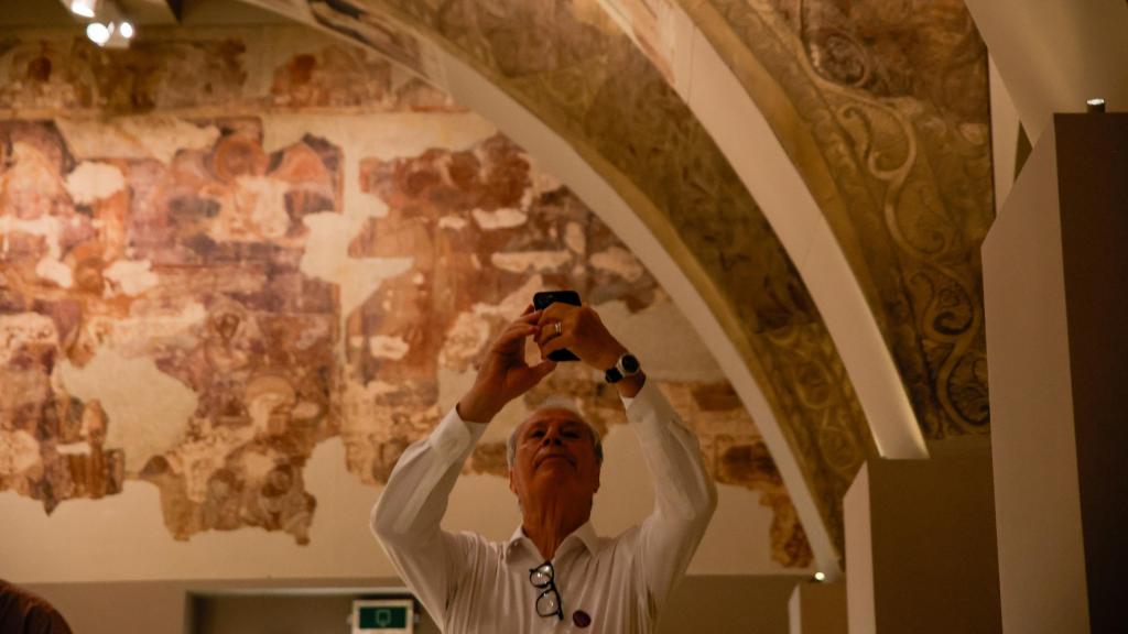 Un hombre fotografía las pinturas del Monasterio de Sijena, expuestas en el MNAC