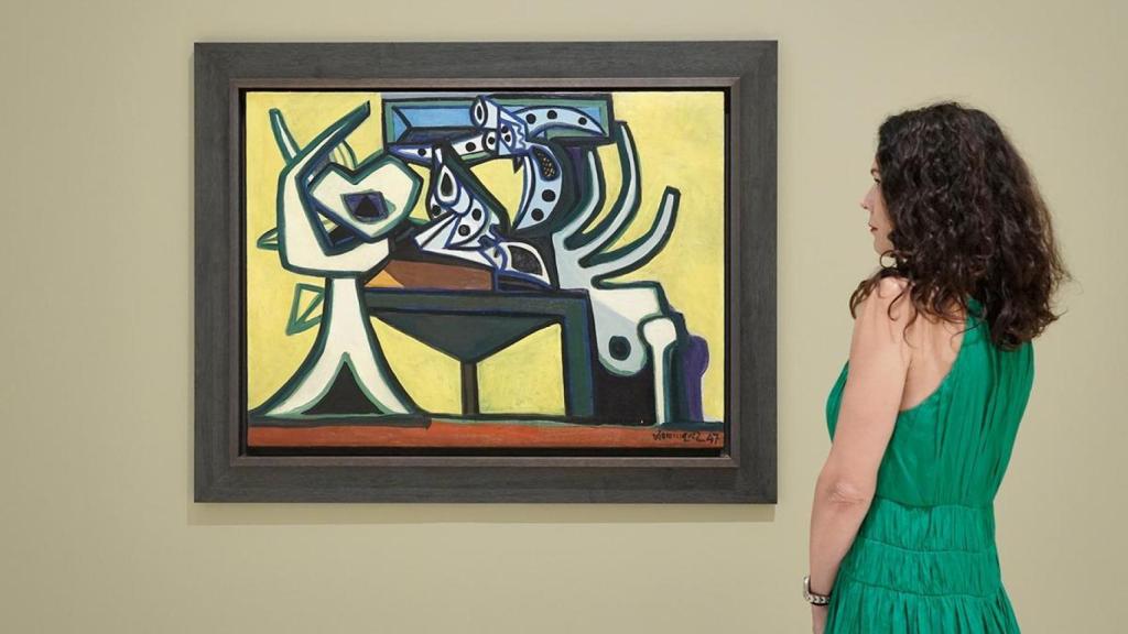 Una mujer observa el lienzo ‘Naturaleza muerta con revólver’ (1957), de Óscar Domínguez.