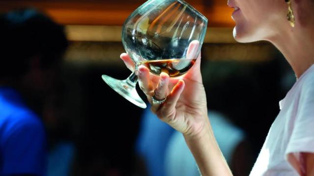 Mujer bebe una copa de una bebida espirituosa