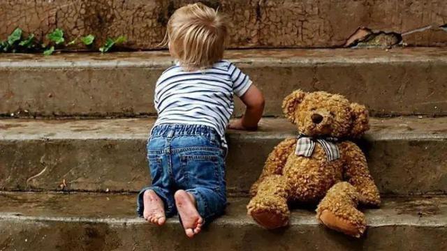 Niño pequeño al lado de un peluche