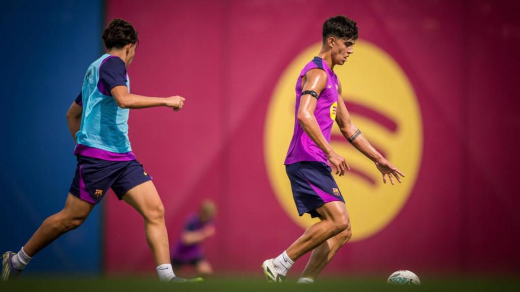 Marc Bernal condueix la pilota en un entrenament del Barça, perseguit per Toni Fernández