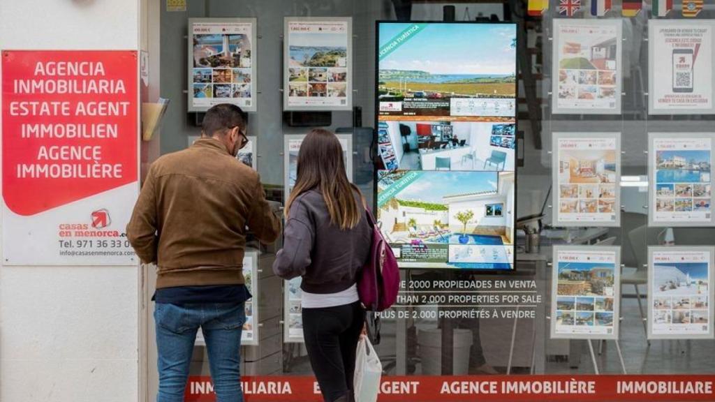 Persones mirant l'aparador de la immobiliària / EFE