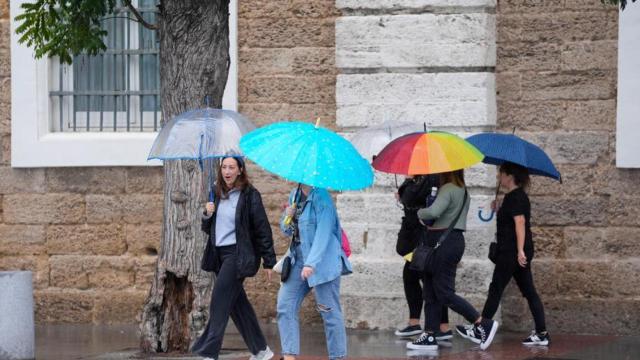 Transeuntes bajo sus paraguas durante la intensa lluvia. A 11 de octubre de 2024, en Cádiz (Andalucía, España).