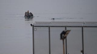 Un joven migrante trata de huir a nado, tras ser interceptado por la policía cuando intentaba cruzar la valla de Ceuta, el 12 de agosto de 2025