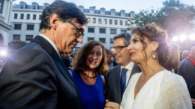 El 'president' Salvador Illa conversa con la vicepresidenta primera, María Jesús Montero, durante la celebración de la Diada Nacional de Cataluña en la Delegación del Govern en Madrid