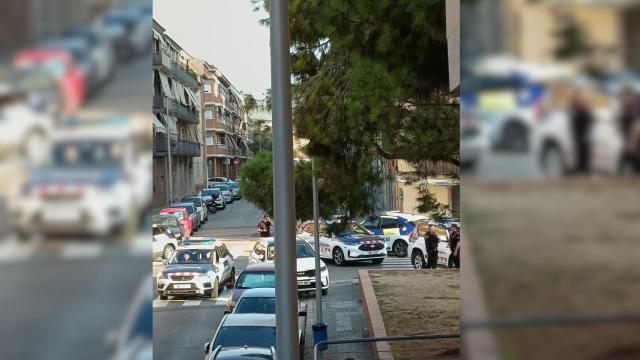 Imagen de los coches de la Policía Local y los Mossos en la plaza donde se encontró la maleta con medio cuerpo descuartizado