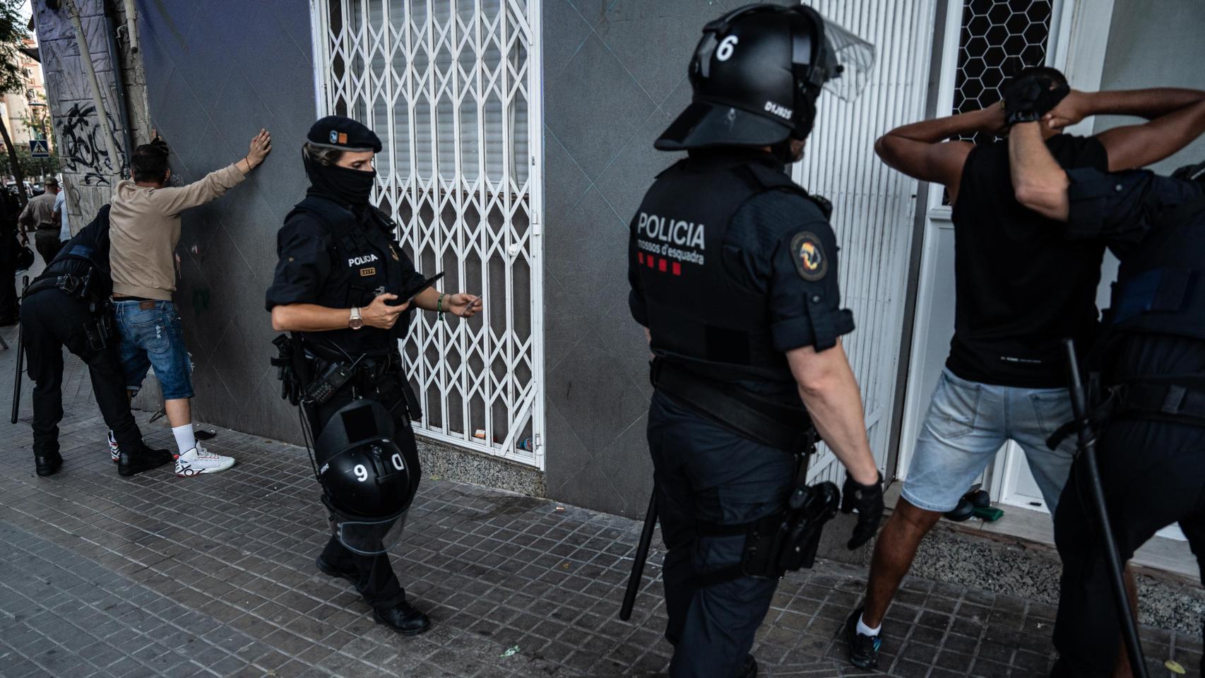 Agentes de la Brimo de los Mossos d'Esquadra cacheando a dos personas que se han identificado