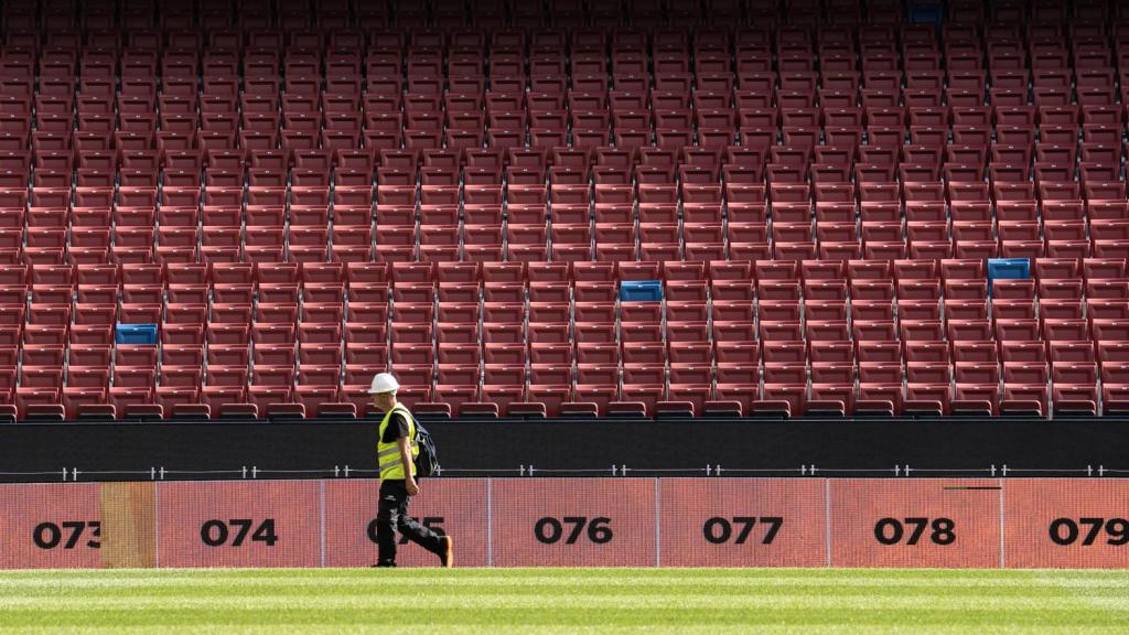 Un obrero se pasea por el césped del Camp Nou en obras