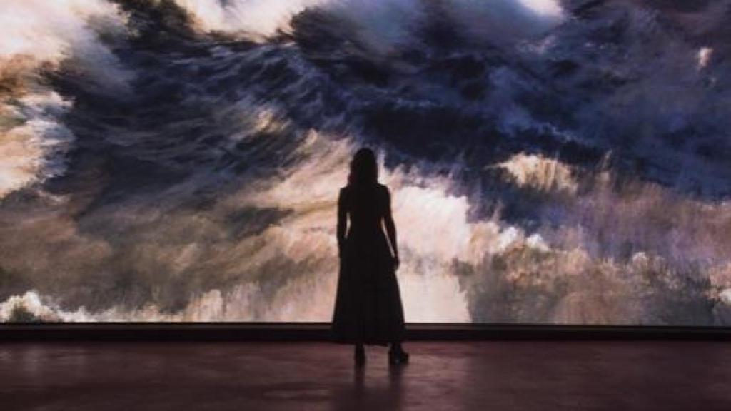 Mujer observando una muestra de Storms, de Quayola