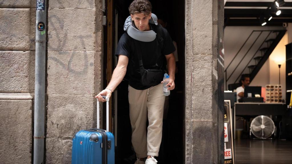 Un turista sale de una finca de pisos turísticos con una maleta en el centro de Barcelona