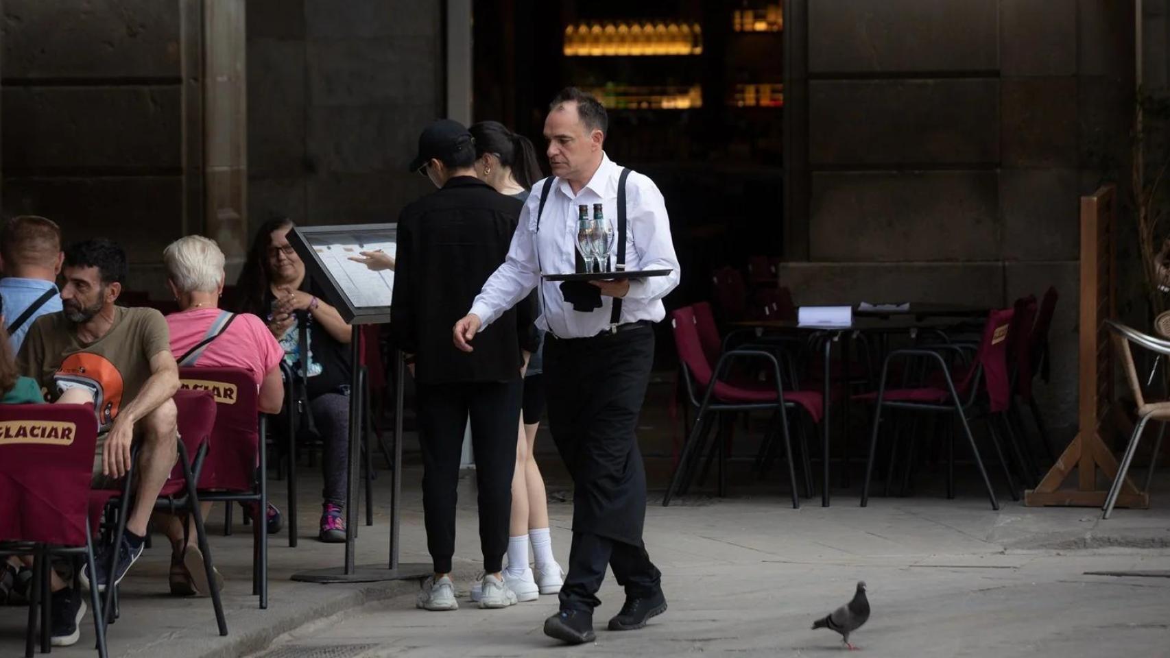 Un camarero atiende a sus clientes en una terraza