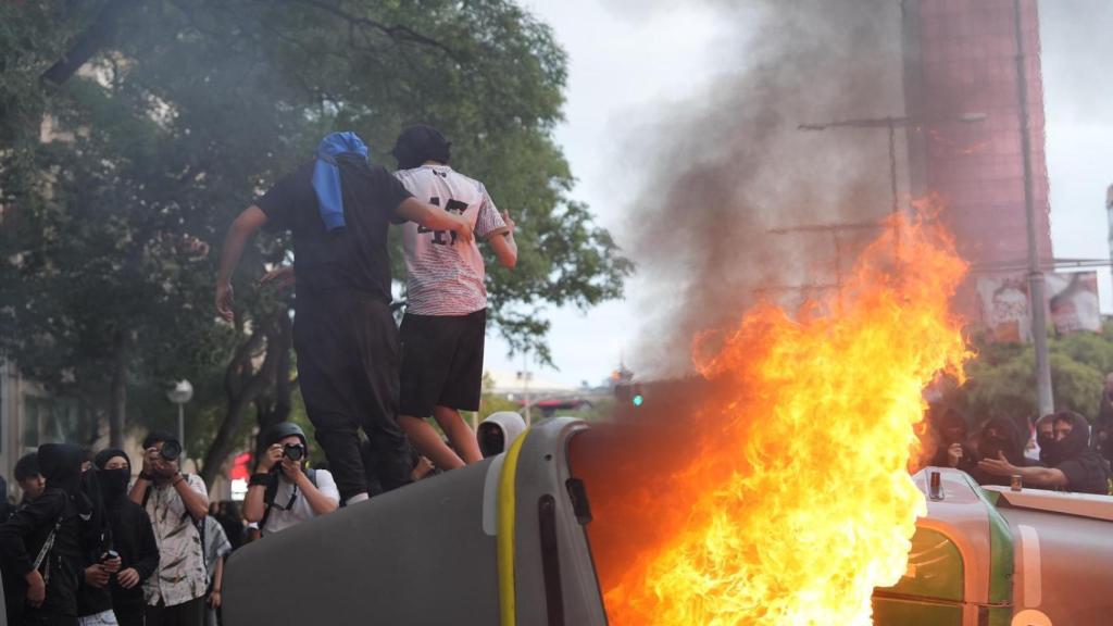 Dos jóvenes subidos encima de un contenedor ardiendo en la manifestación propalestina de este miércoles 15 de octubre en Barcelona