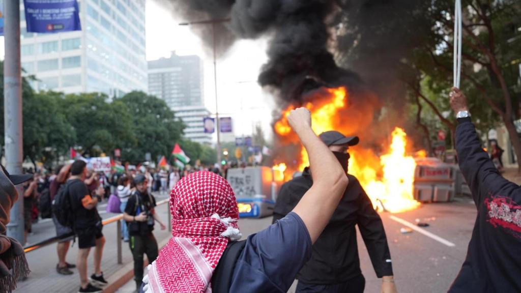 Detalle de un vándalo ataviado con un pañuelo palestino ante una barricada ardiendo en la calle Tarragona de Barcelona