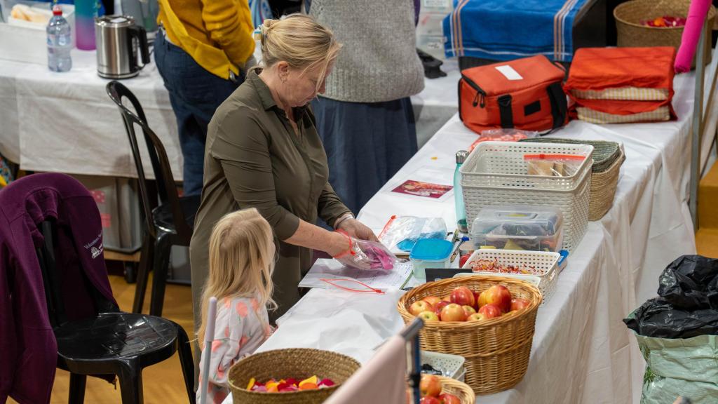 Una niña ayuda a su madre, voluntaria de Amma, a preparar el almuerzo de los voluntarios del evento en Granollers