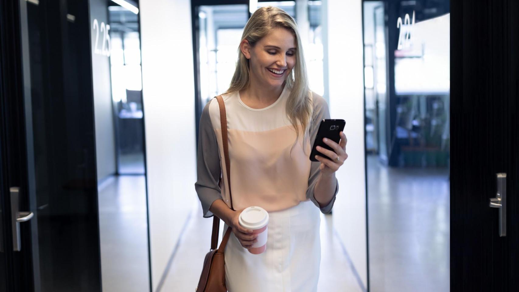 Mujer sonríe mientras consulta su móvil