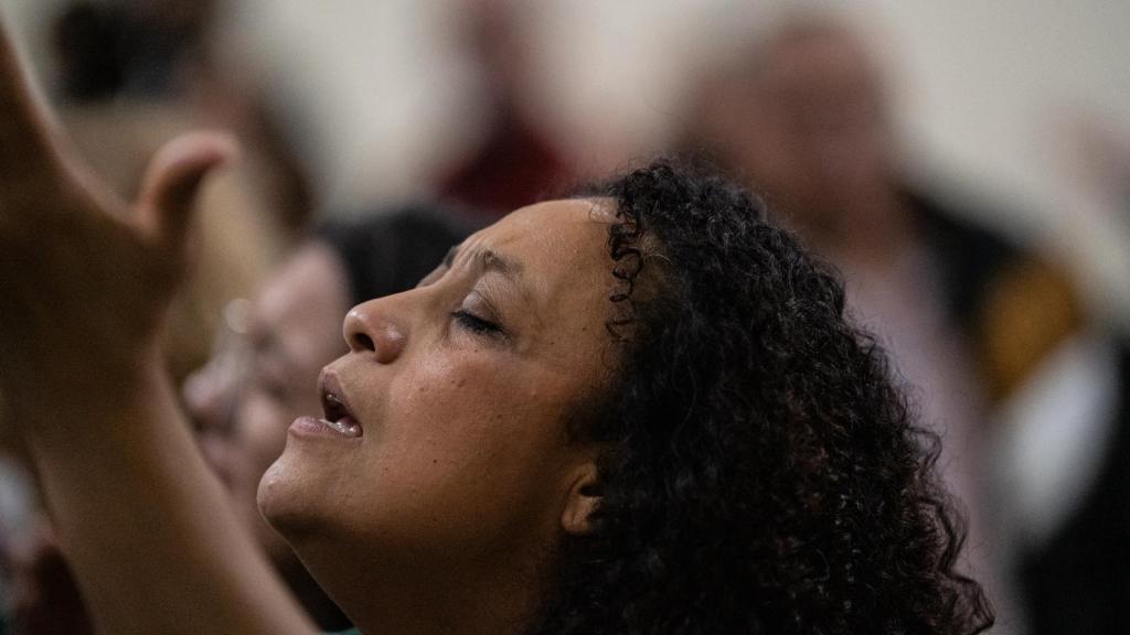 Una mujer canta con los brazos en alto durante un servicio en la Iglesia Elim de Girona