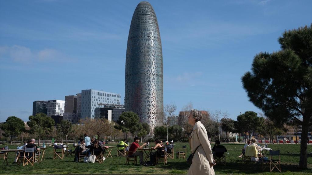 Varias personas sentadas en mesas en el parque de Les Glòries (Barcelona)