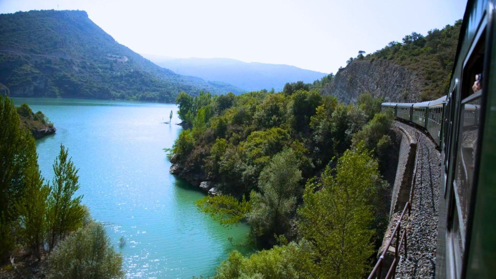 Un viajero se asoma a ver un lago en un tren