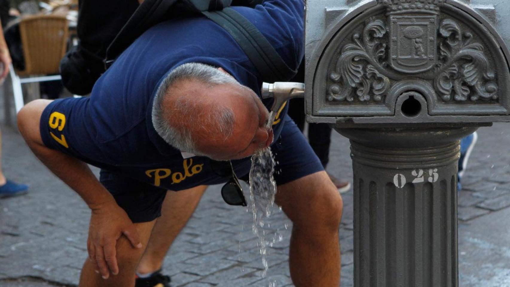 Una persona bebe agua de una fuente pública