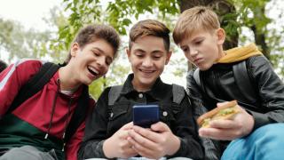 Tres adolescentes miran un mismo teléfono móvil