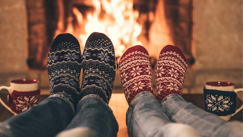Personas calentándose los pies cerca de una chimenea