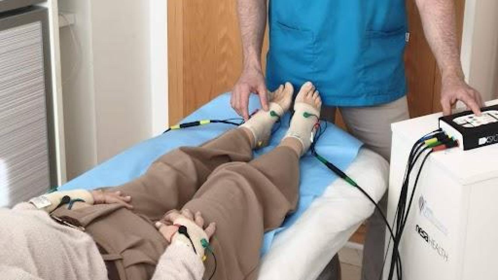 Persona tumbada en una camilla con bandas de tratamiento en los pies