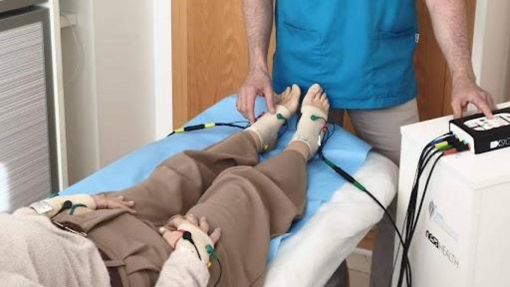 Persona tumbada en una camilla con bandas de tratamiento en los pies