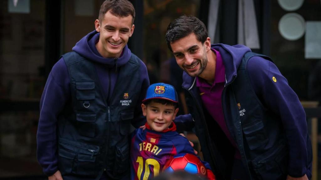 Marc Casadó y Ferran Torres posan con un niño en la Casa dels Xuklis