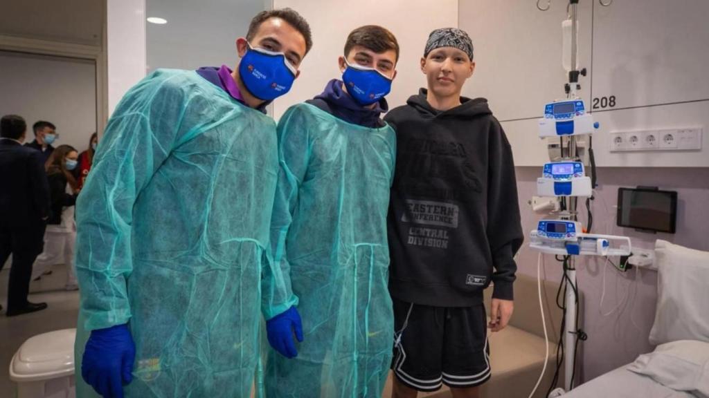 Éric García i Pedri somriuen amb un nen ingressat en un hospital de Barcelona