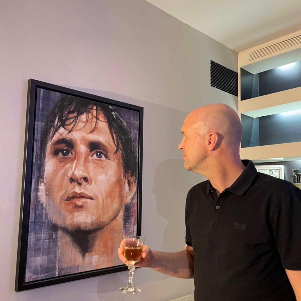 Jordi Cruyff observa un quadre de Johan Cruyff amb una copa a la mà