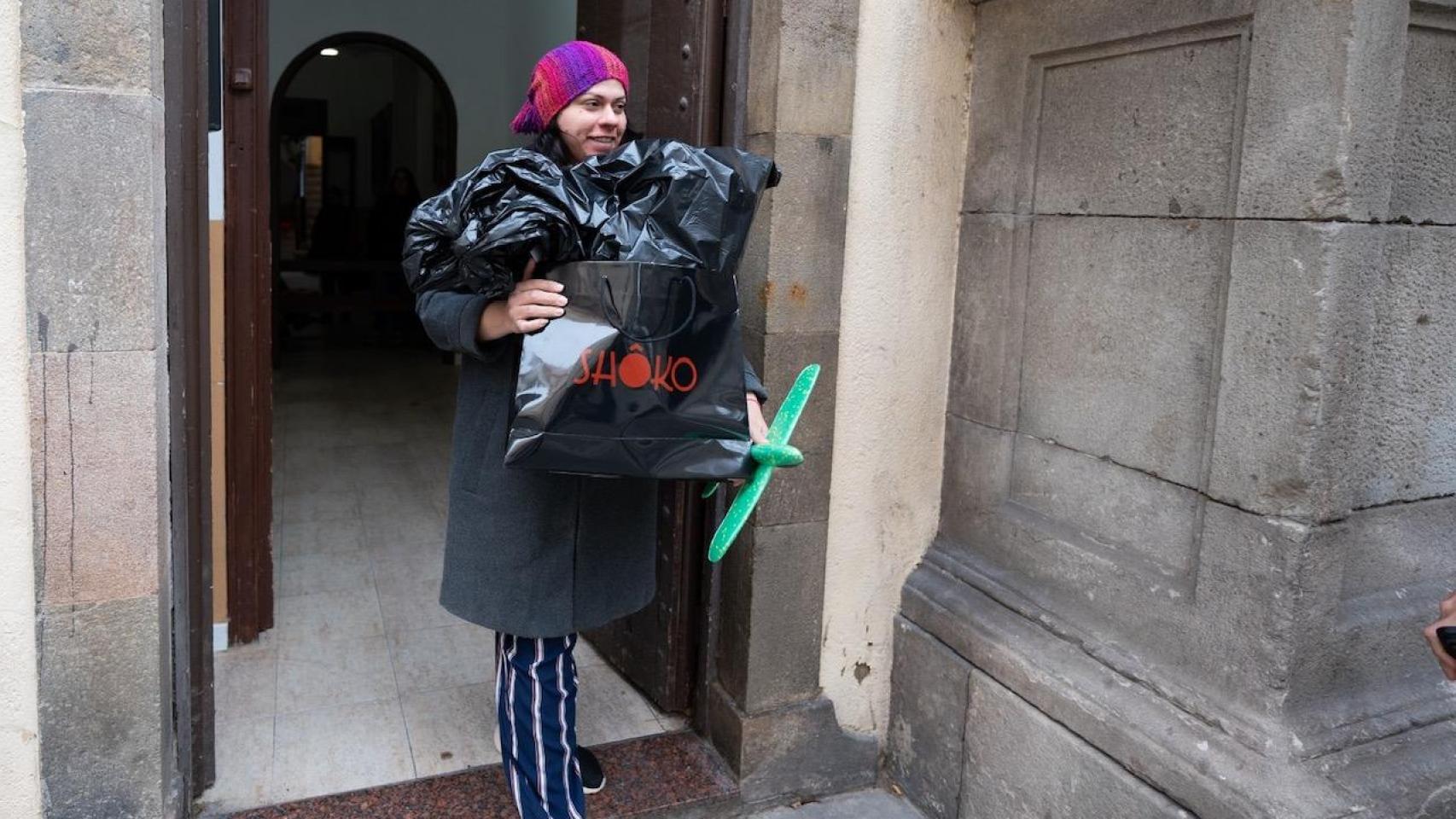 Una mujer, recogiendo juguetes de la entrega solidaria del barrio de la Barceloneta