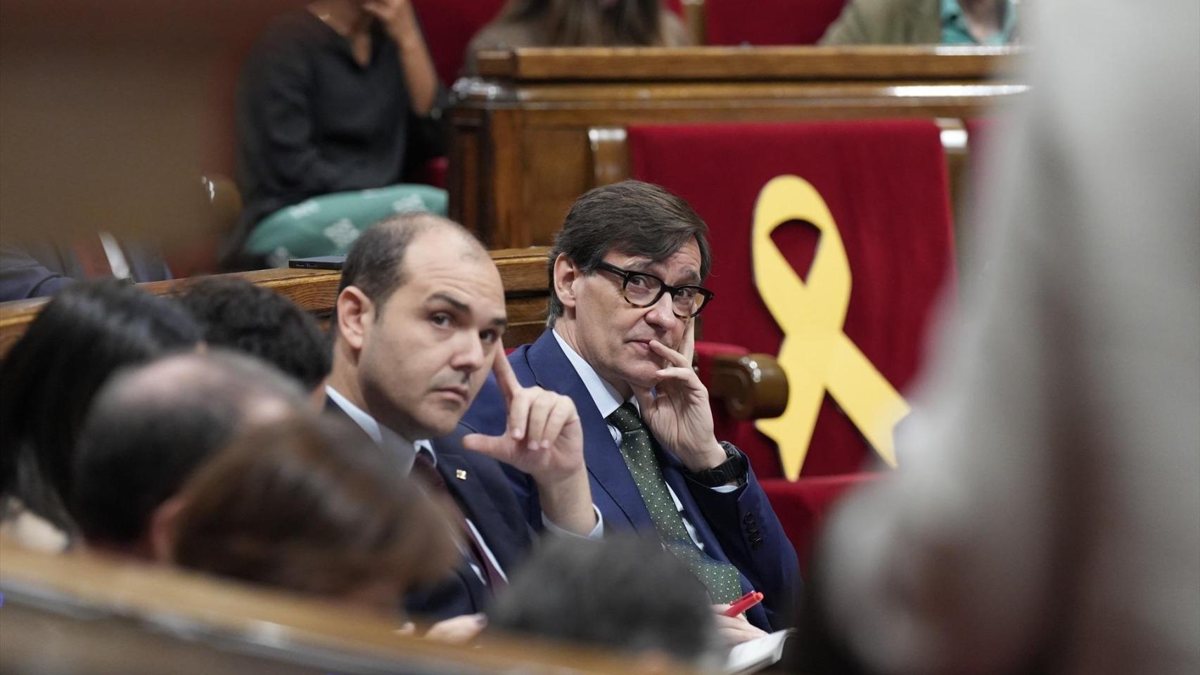 El presidente de la Generalitat, Salvador Illa, junto al 'conseller' de la Presidencia, Albert Dalmau, y un lazo amarillo en el escaño de Carles Puigdemont, en el Parlament